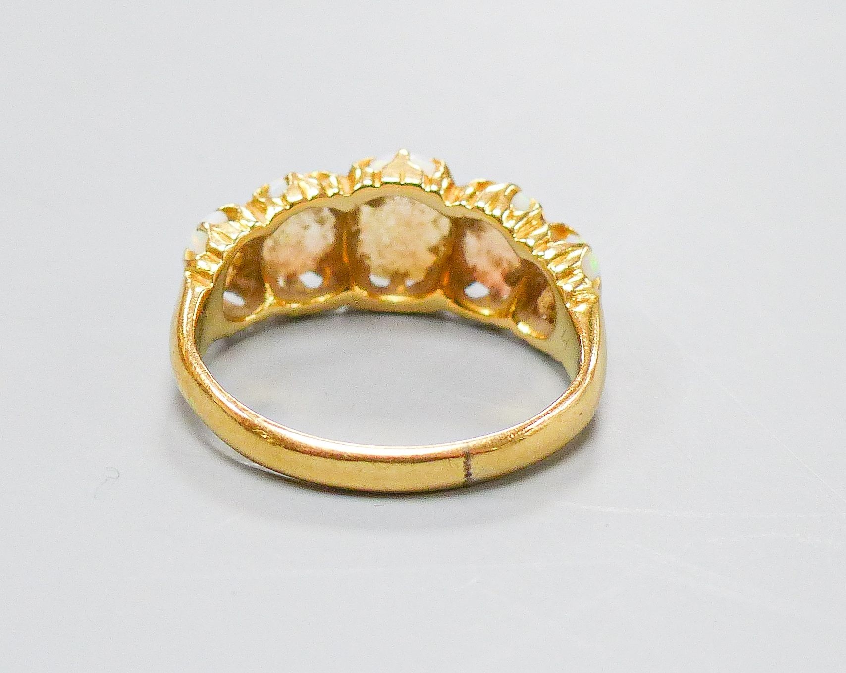 An Edwardian 18ct gold and graduated five stone white opal set half hoop ring, size K, gross 3.8 grams.